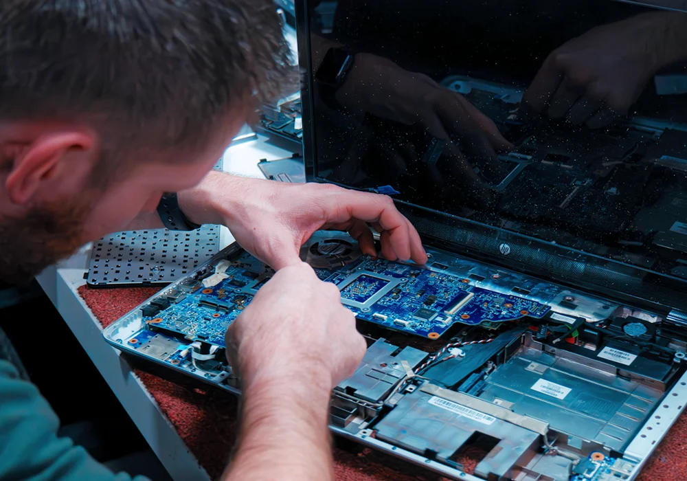 Photographie de Jonathan Dumont en train de réparer un ordinateur portable.